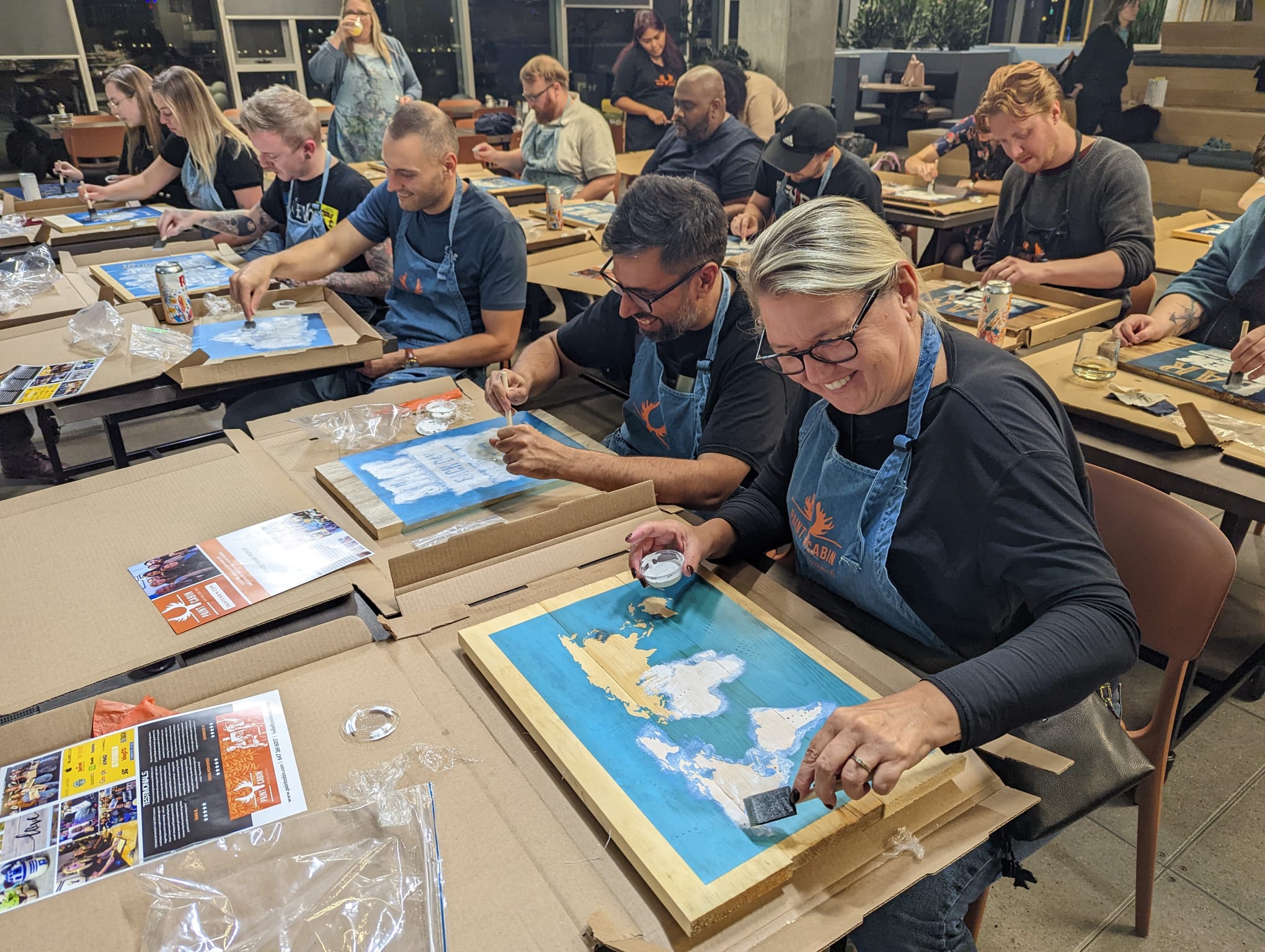 Team smiling and participating in a wood sign activity during a mobile offsite event with Paint Cabin